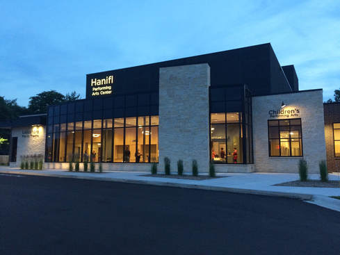 Exterior photo of Hanifl Performing Arts Center's glassed lobby at night.